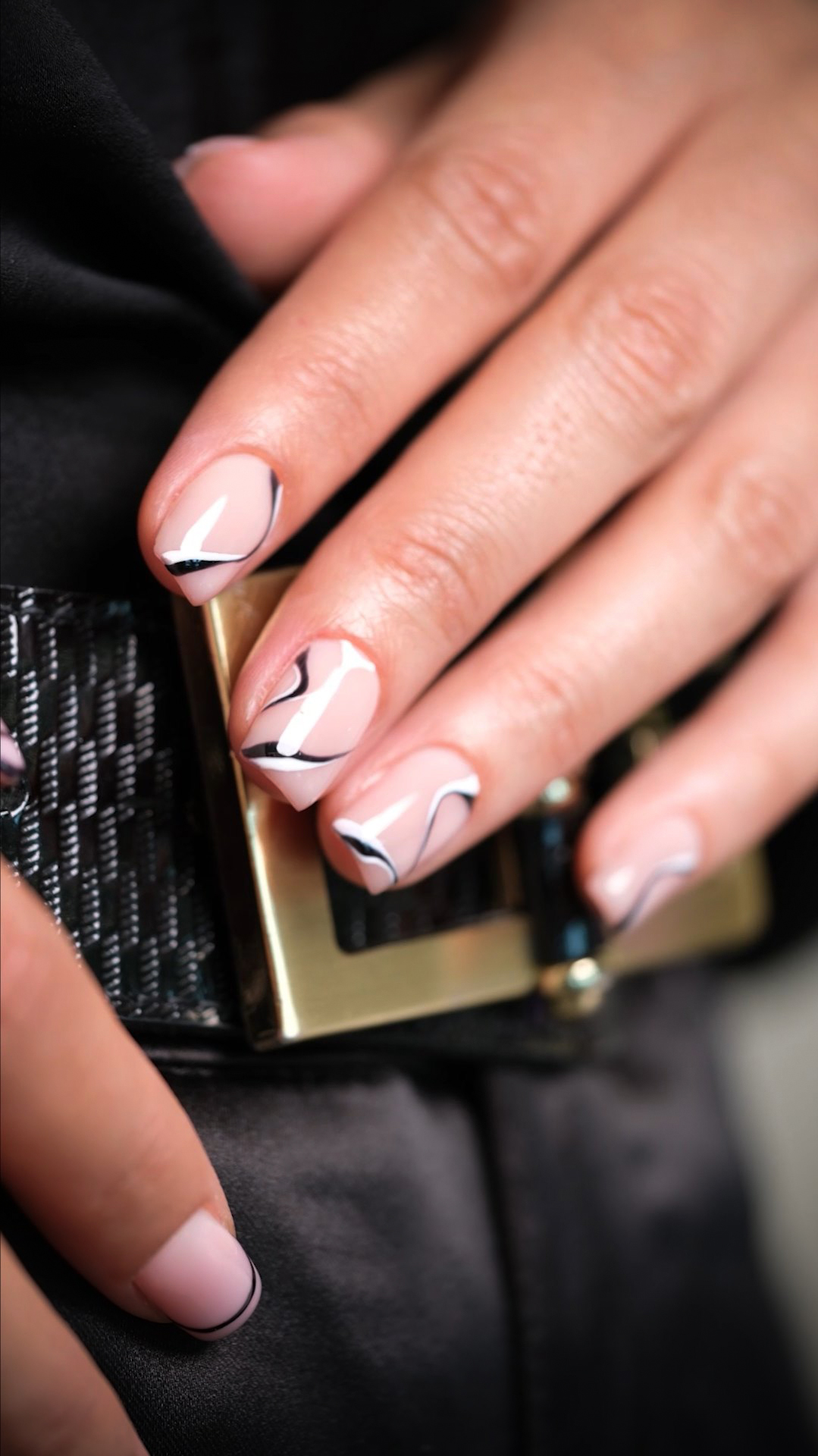 Close-up of stylish nail art with a black and white abstract design on perfectly manicured nails, showcasing luxury nail services.