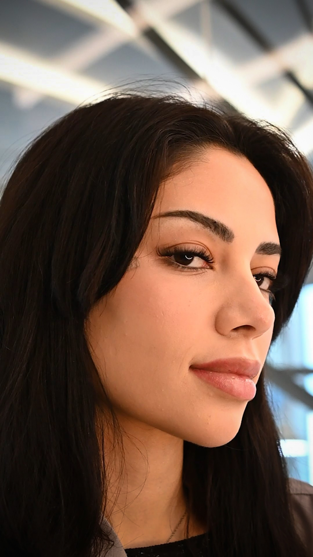 Close-up of a woman with flawless makeup and voluminous eyelashes, highlighting professional lash extension services at the salon.