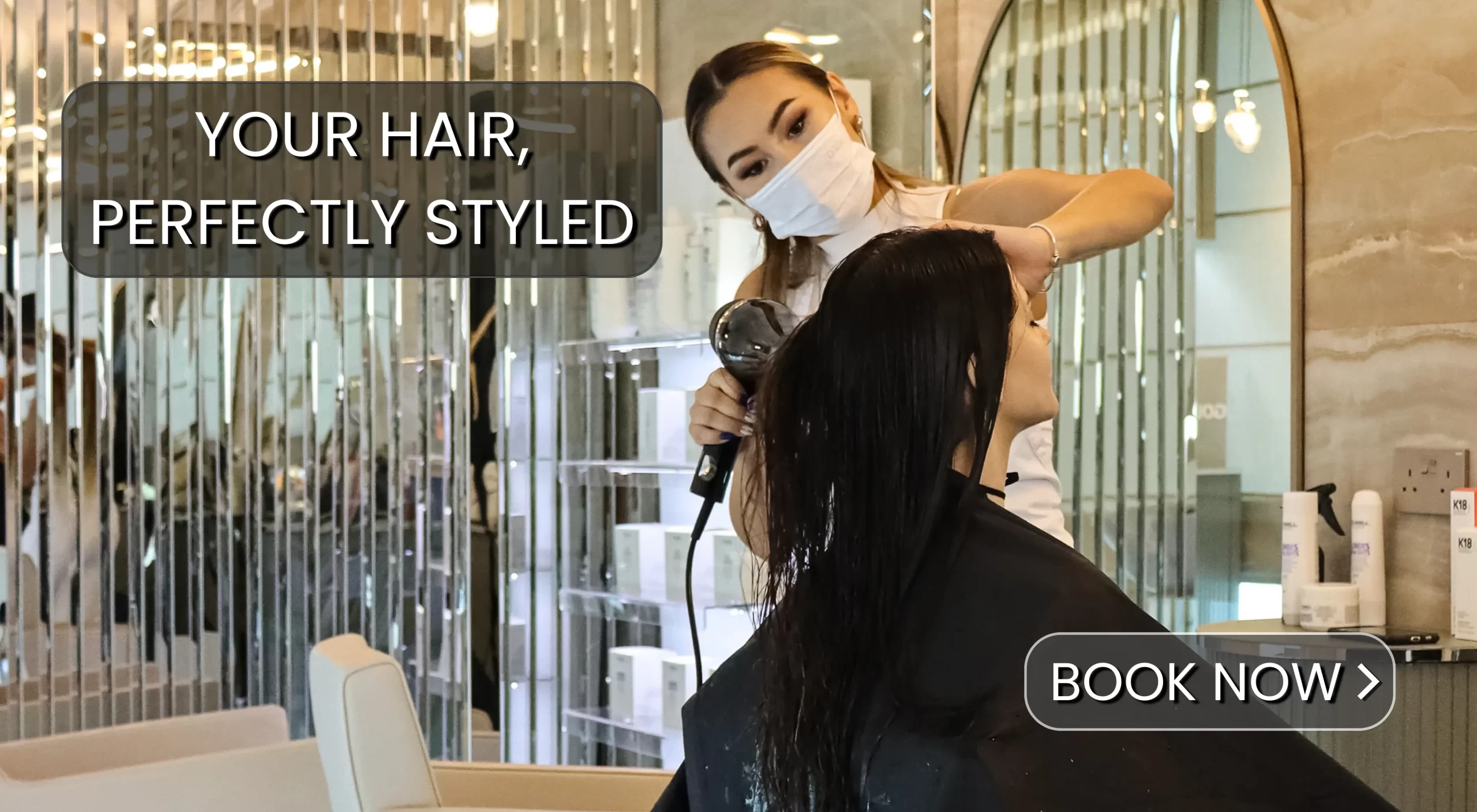 A woman blow drying and styling another woman's hair in an elegance looking beauty salon with the words "Your hair, perfectly styled" as an overlay text.